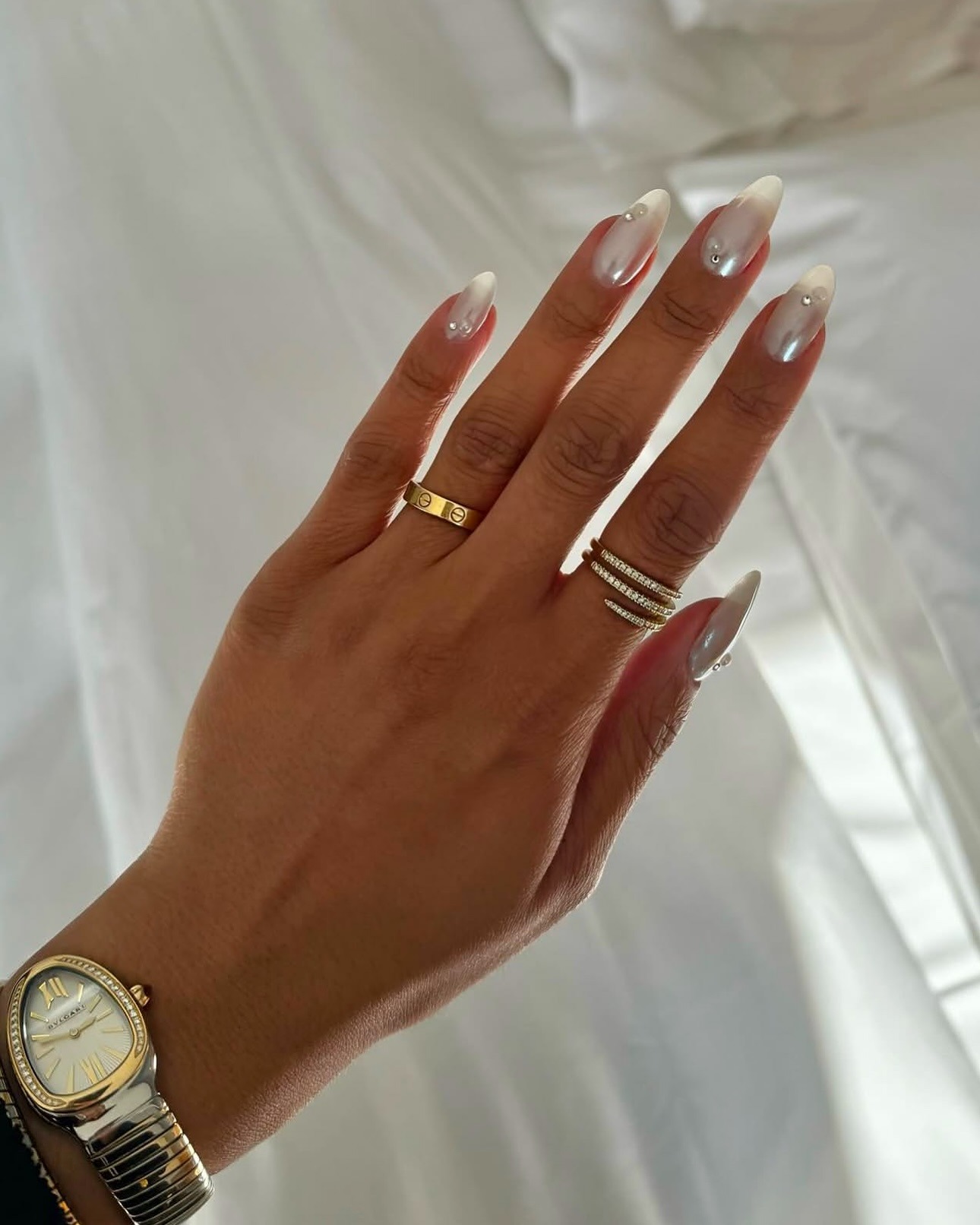 Person wearing milky white jelly nail polish with embellishments.