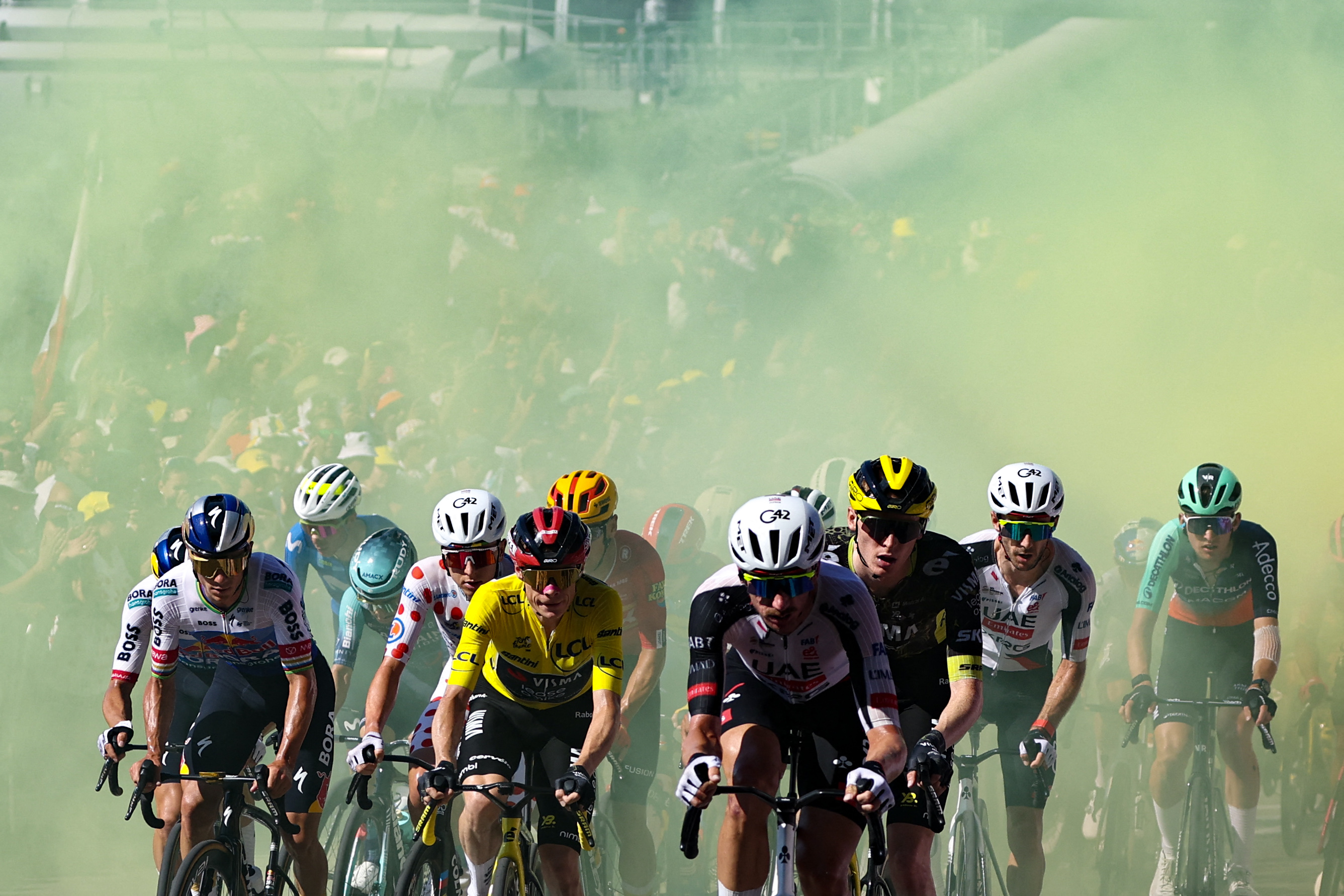 Red Bull - BORA - hansgrohe team's Belgian rider Remco Evenepoel (L), UAE Team Emirates - XRG's Slovenian rider Tadej Pogacar wearing the climber's dotted jersey (2nd L), Team Visma | Lease a Bike's Danish rider Jonas Vingegaard wearing the overall leader's yellow jersey (C), UAE Team Emirates - XRG's US rider Brandon McNulty (center R) and riders emerge from yellow smoke as they cycle in the ascent of Montjuic Palace in the final kilometers of the 2nd stage of the 113th edition of the Tour de France cycling race, 168,5 km between Tarragona and Barcelona in northeastern Spain, on July 5, 2026. (Photo by Anne-Christine POUJOULAT / AFP)