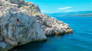Female rock climber deep water solos in the picturesque Adriatic sea