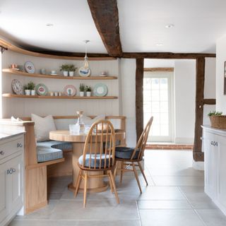 Curved corner seating in white kitchen with beamed ceilings and walls