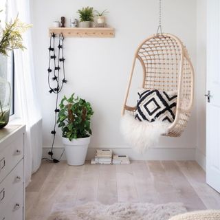 Rattan chair suspended in the corner of a room with cream walls and pale wooden flooring. Sofie and Rob Hepworth's renovated five bedroom semi detached Edwardian house in North East London.