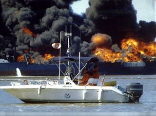 Jupiter, a gasoline tanker for Cleveland Tankers ablaze in the Saginaw River near Bay City, Michigan. Turbulence from a passing freighter pulled Jupiter away from dock while it was offloading, breaking her hoses and starting the fire. One crewman died, se