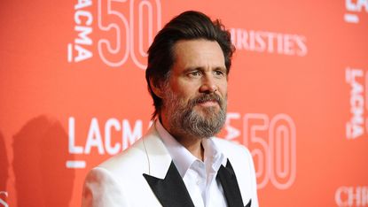 Jim Carrey with a thick beard wearing a white tux jacket.