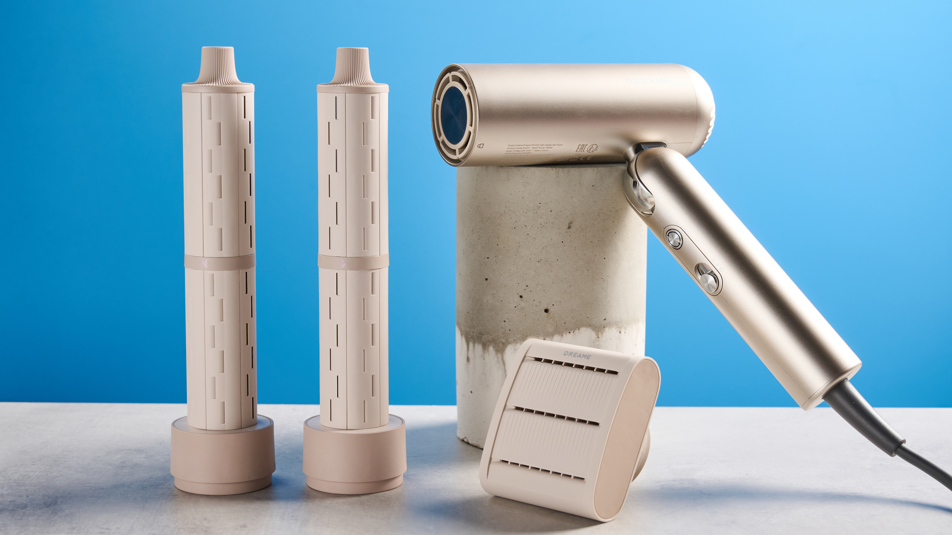 The Dreame Pocket Neo in gold with attachments photographed in front of a blue background.