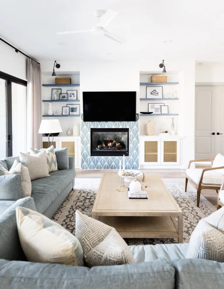 blue and white living room with bookcase alcoves, blue tiles around fire surround and black wall lights