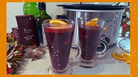 Two glasses of mulled wine beside a slow cooker