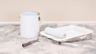 A paint tray and roller next to a can of white paint
