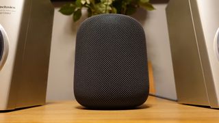  Apple HomePod dalam Space Grey di atas meja di antara dua speaker