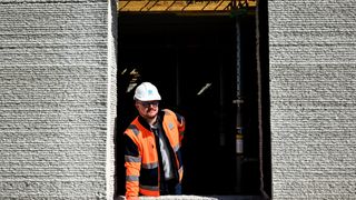 worker in the windows of a 3D-printed house