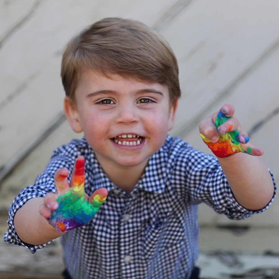 Prince Louis holding up paint covered hands and smiling