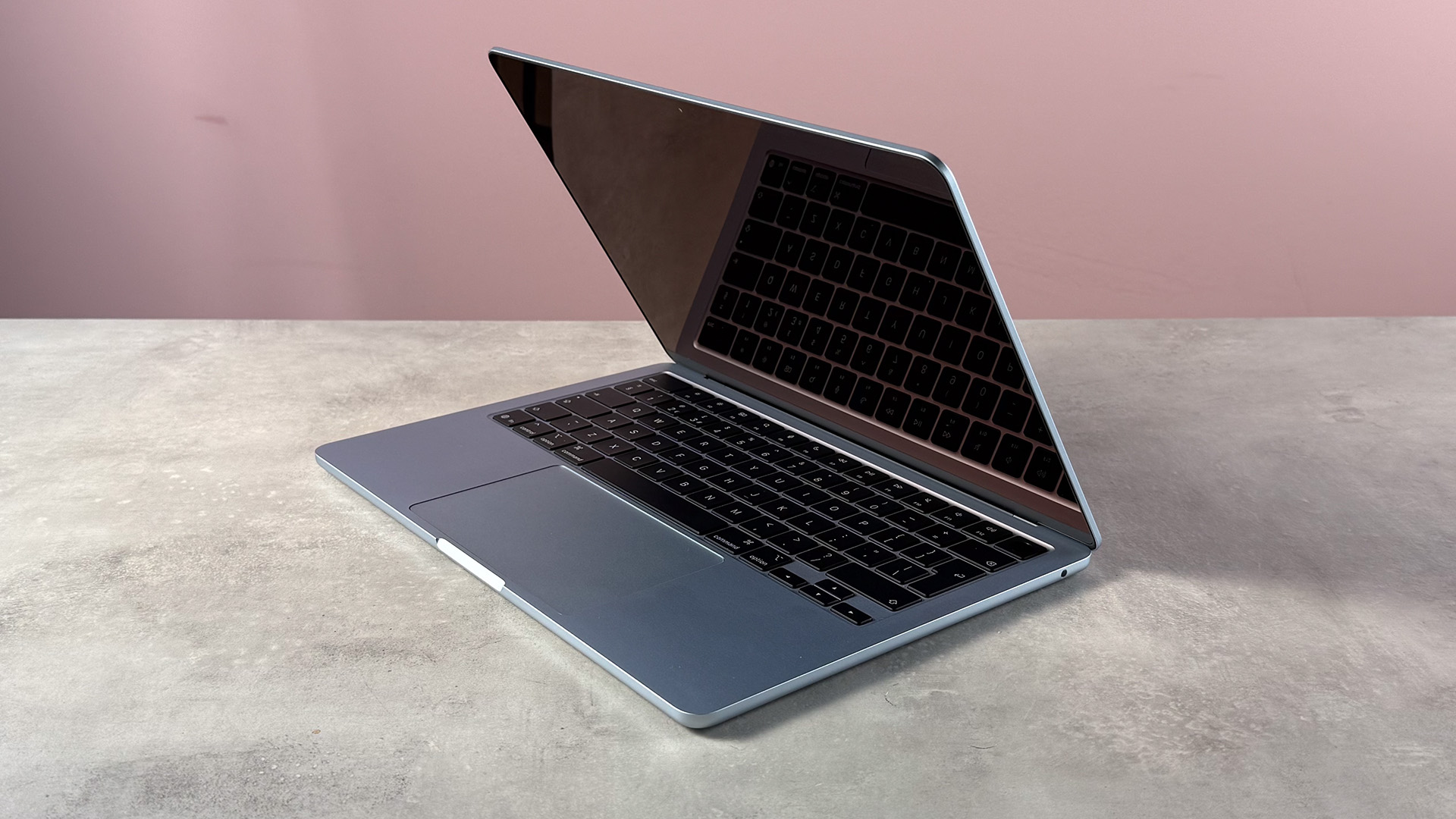 The MacBook Air M5 folded slightly closed, showing a reflection of the keyboard in the screen.