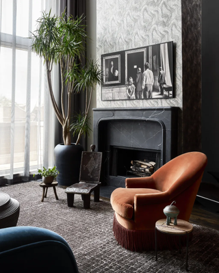 A dark themed room with a black fireplace and an orange accent chair