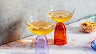 side shot of two colorful cocktail glassed filled with a golden-hued liquid