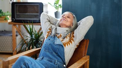 Older woman sitting indoors at home, looking very relaxed.