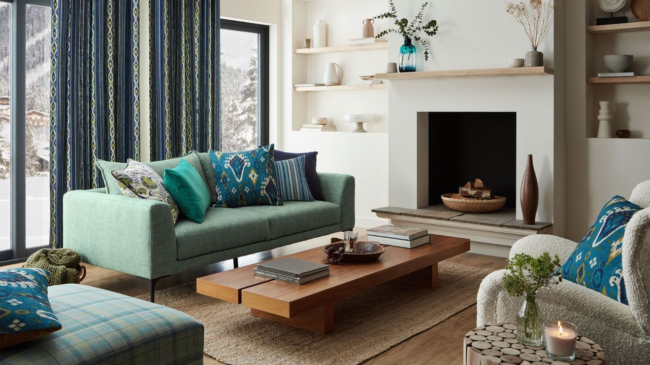 A chalet living room with a green sofa and a low wooden coffee table infront of a large open fireplace, unlit