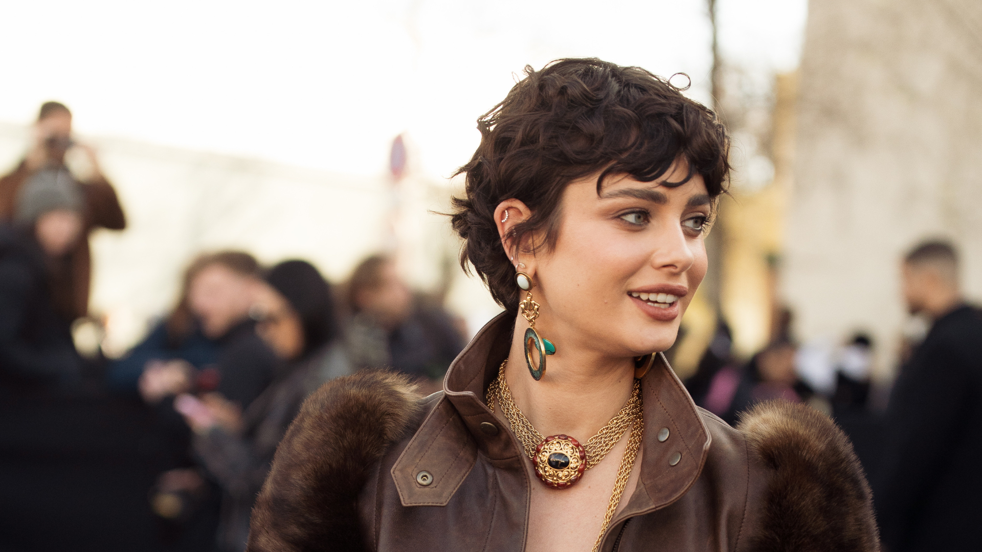 Grown-out pixie Taylor Hill wears green top, brown leather jacket with fur sleeves, brown trousers, gold decorated jewellery outside the Chloe fashion show during the Womenswear Fall/Winter 2025/2026 as part of Paris Fashion Week on March 06, 2025 in Paris, France