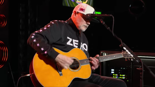 A picture of Billy Corgan performing live with an acoustic guitar