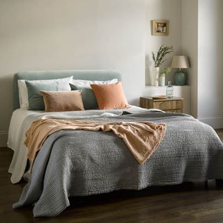 bed with pastel linen quilt and sheets