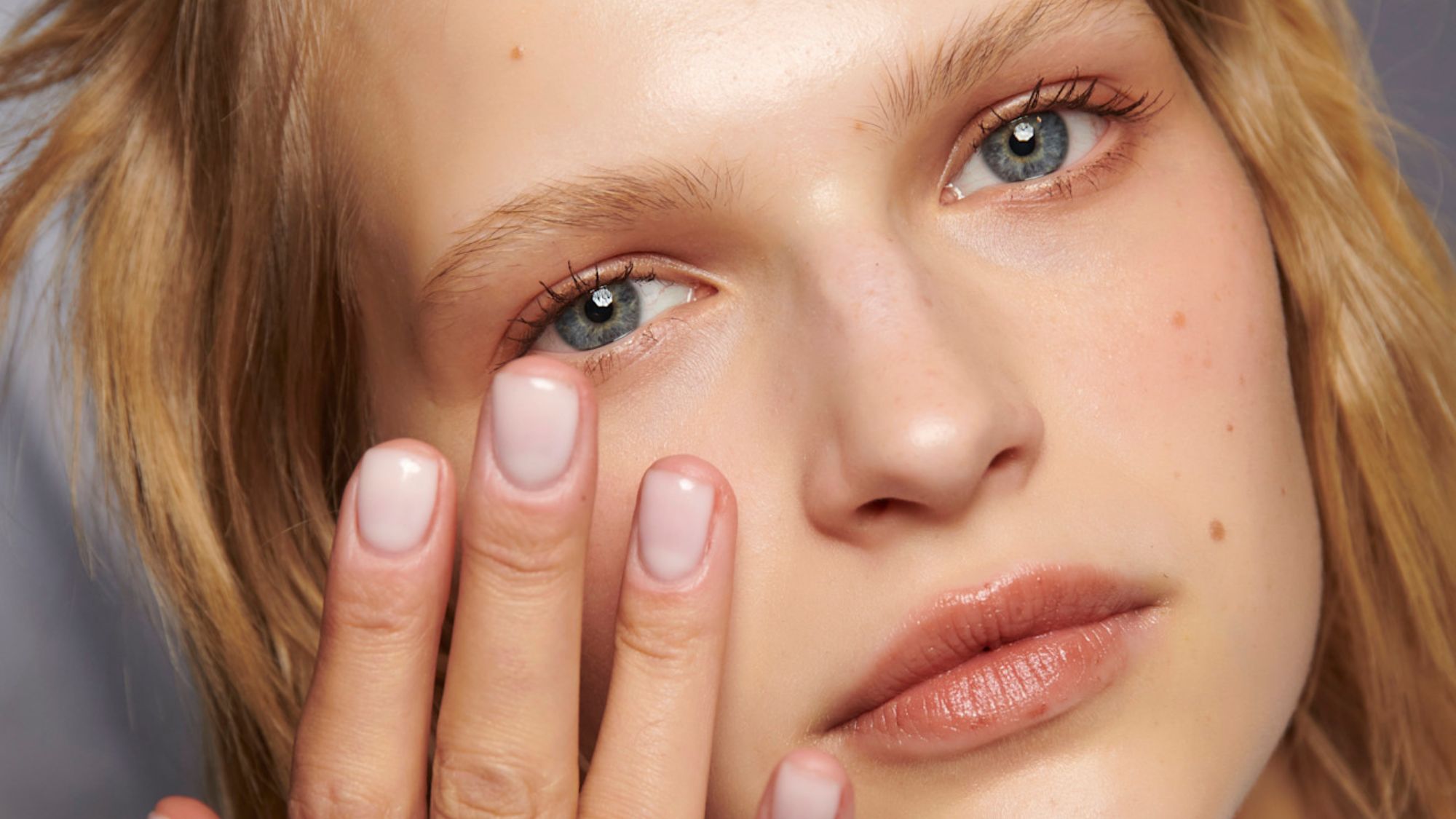 blonde model with glowing skin applying skincare