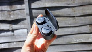 a hand holding the nuratrue wireless earbuds in their charging case