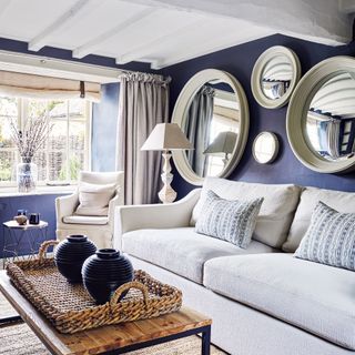 Living room with white ceiling and sofa, blue walls and collection of mirrors