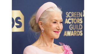 Helen Mirren with her long hair in an updo and a pink headband