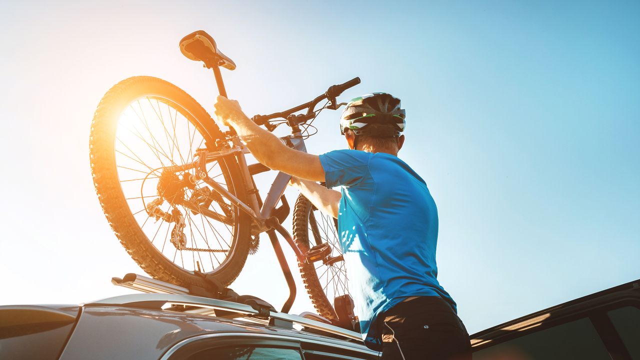 A man putting his bike on top of his car on the best bike rack