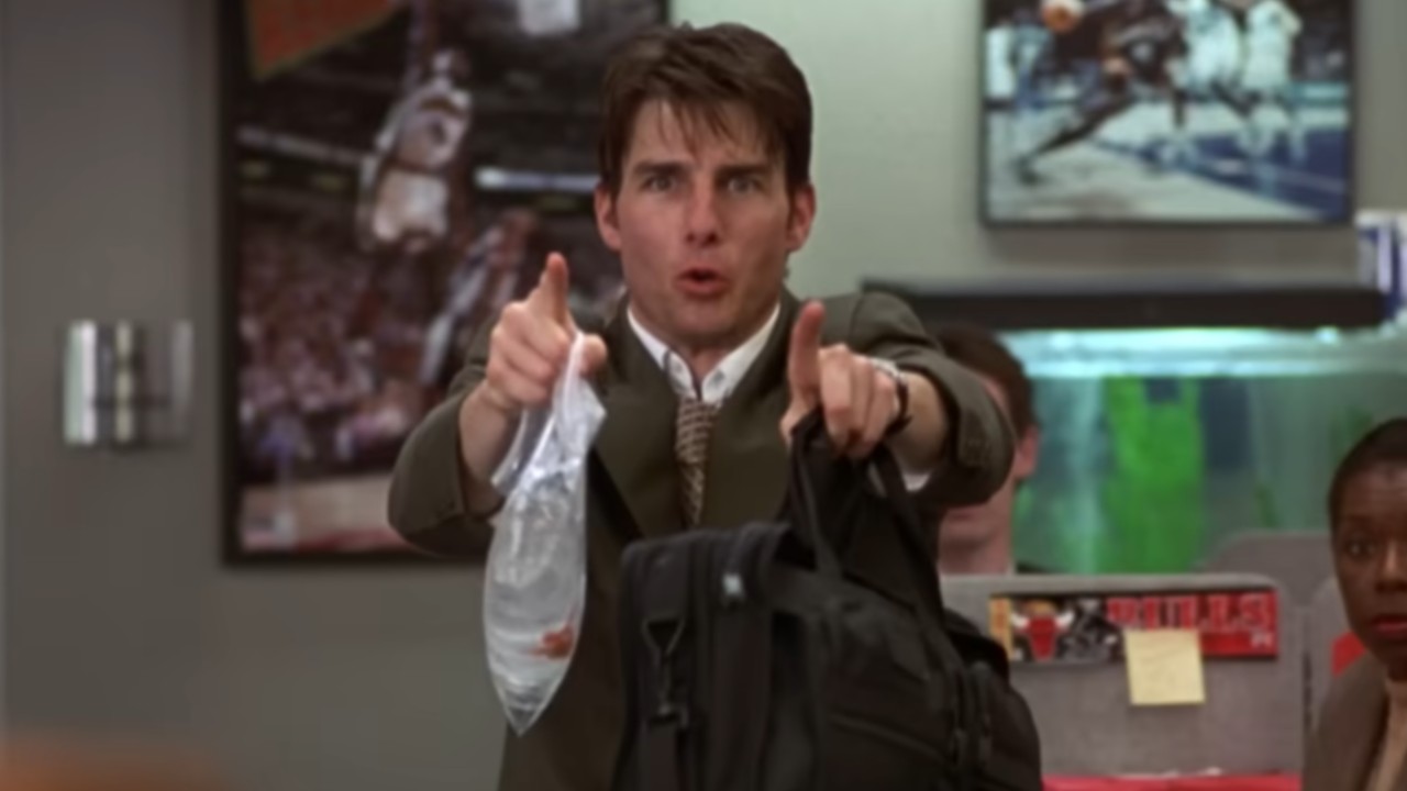 Tom Cruise pointing and yelling while holding a bag with a fish in it in his left hand and a breif case in his right hand in Jerry Maguire.
