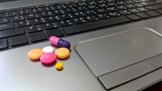 Close up image of pills sitting on a laptop.