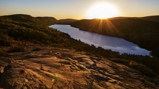 Sunrise above Michigan's Lake of the Clouds. We see a ridge of basalt in the foreground.