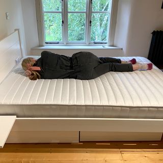 A woman laid on the Dreams Workshop Follows Traditional Spring Mattress with her back to the camera