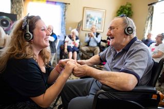 Two people enjoy assistive listening devices from Eversound and Uniguest.