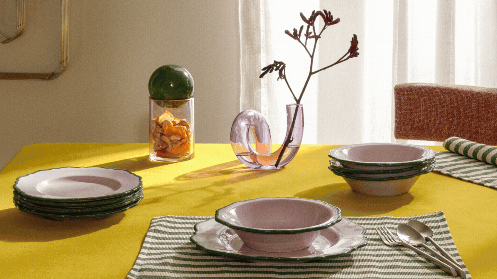gif of dinnerware on different tables, including white dinnerware with scallop shape and dark rim, yellow tablecloth with green-and-pink dinnerware, and a dark tablecloth with round white bowls