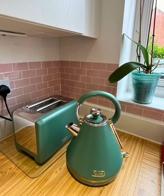 My spotless sage green and stainless steel Tower toaster and kettle set on wooden worktop against pink subway tiled backsplash after cleaning with essential oil removed all marks