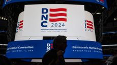 A man walks past the United Center scoreboard displaying the logo for the 2024 Democratic National Convention
