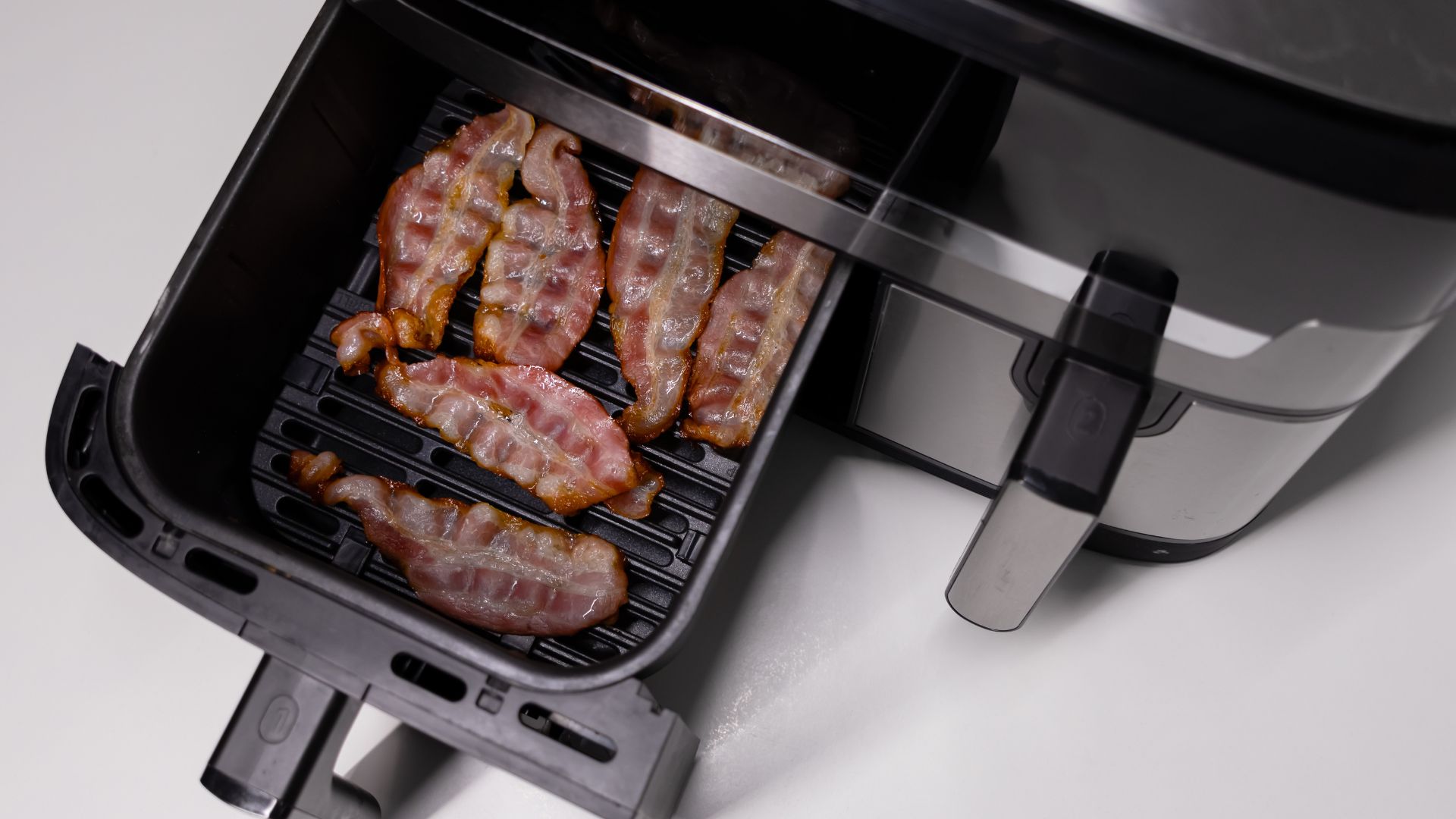picture of air fryer drawer with cooked bacon inside