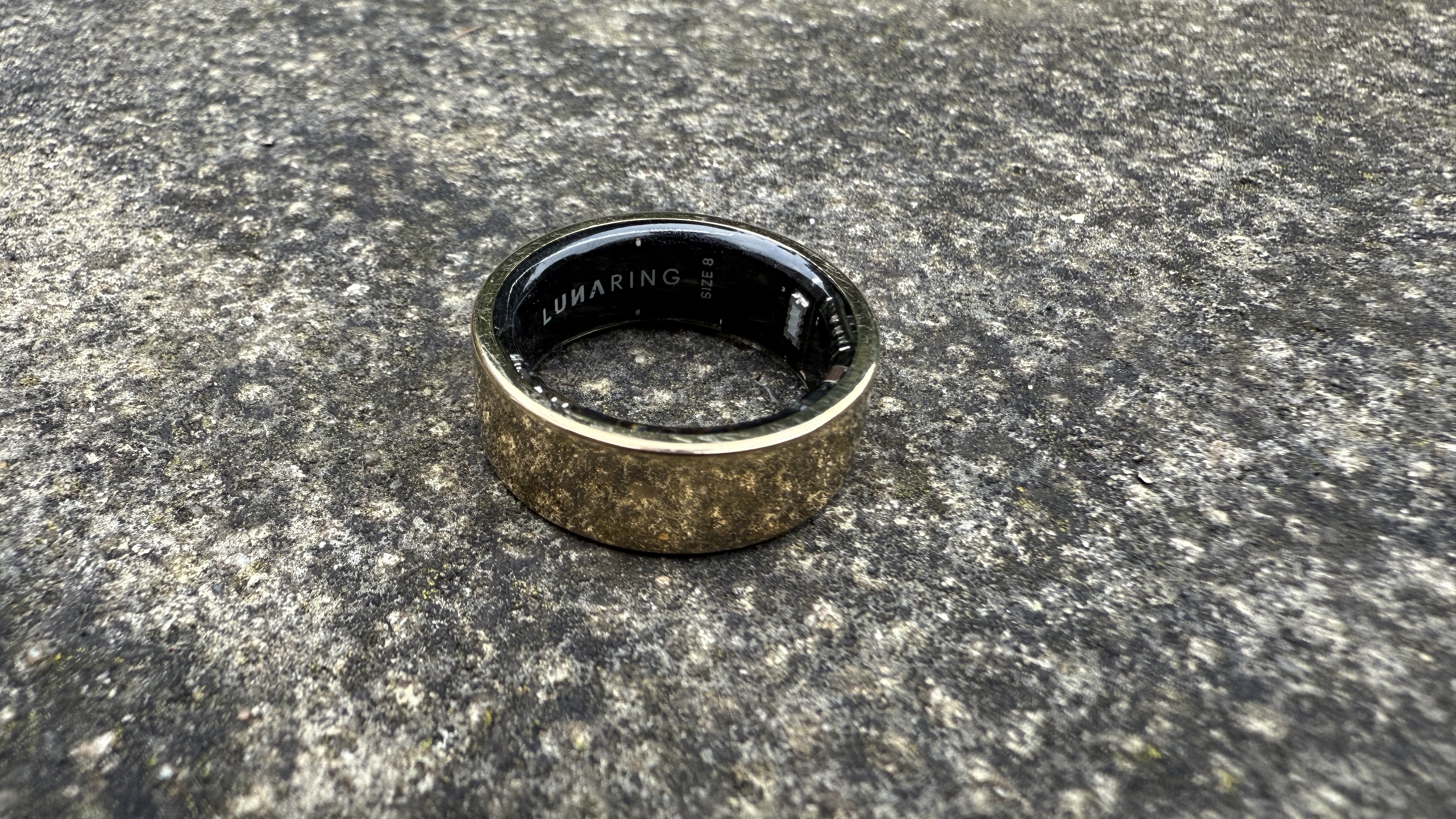 The Luna Ring 2 in gold on a concrete surface