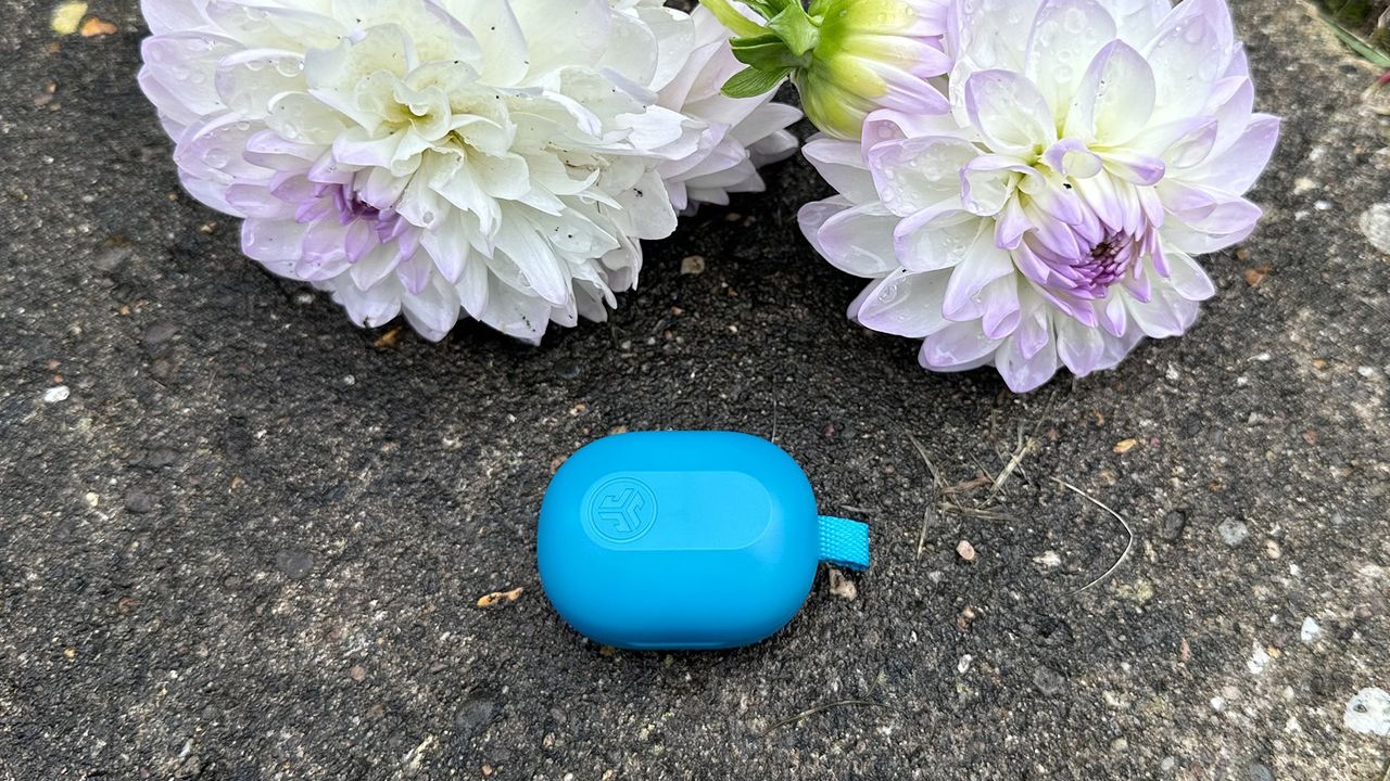 The JLab JBuds Mini inside their case next to flowers