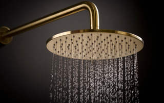 Gold shower head running water with a dark background
