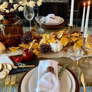 Rustic dining table decor with pine cones and fall leaves