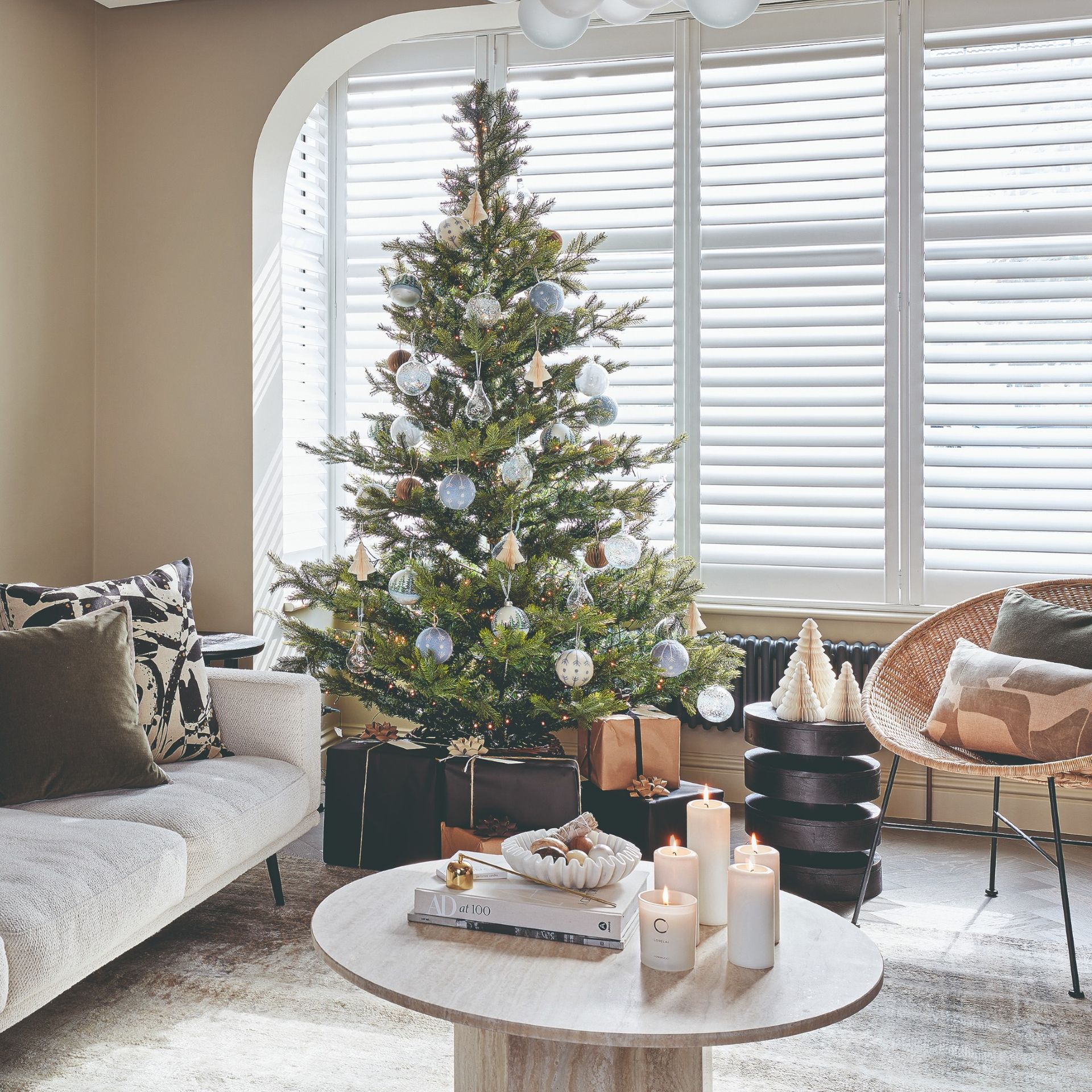 A minimalist living room decorated for Christmas with a traditional green Christmas tree adorned with white glass baubles
