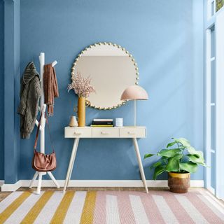 Blue painted hallway with white console table and hanging mirror