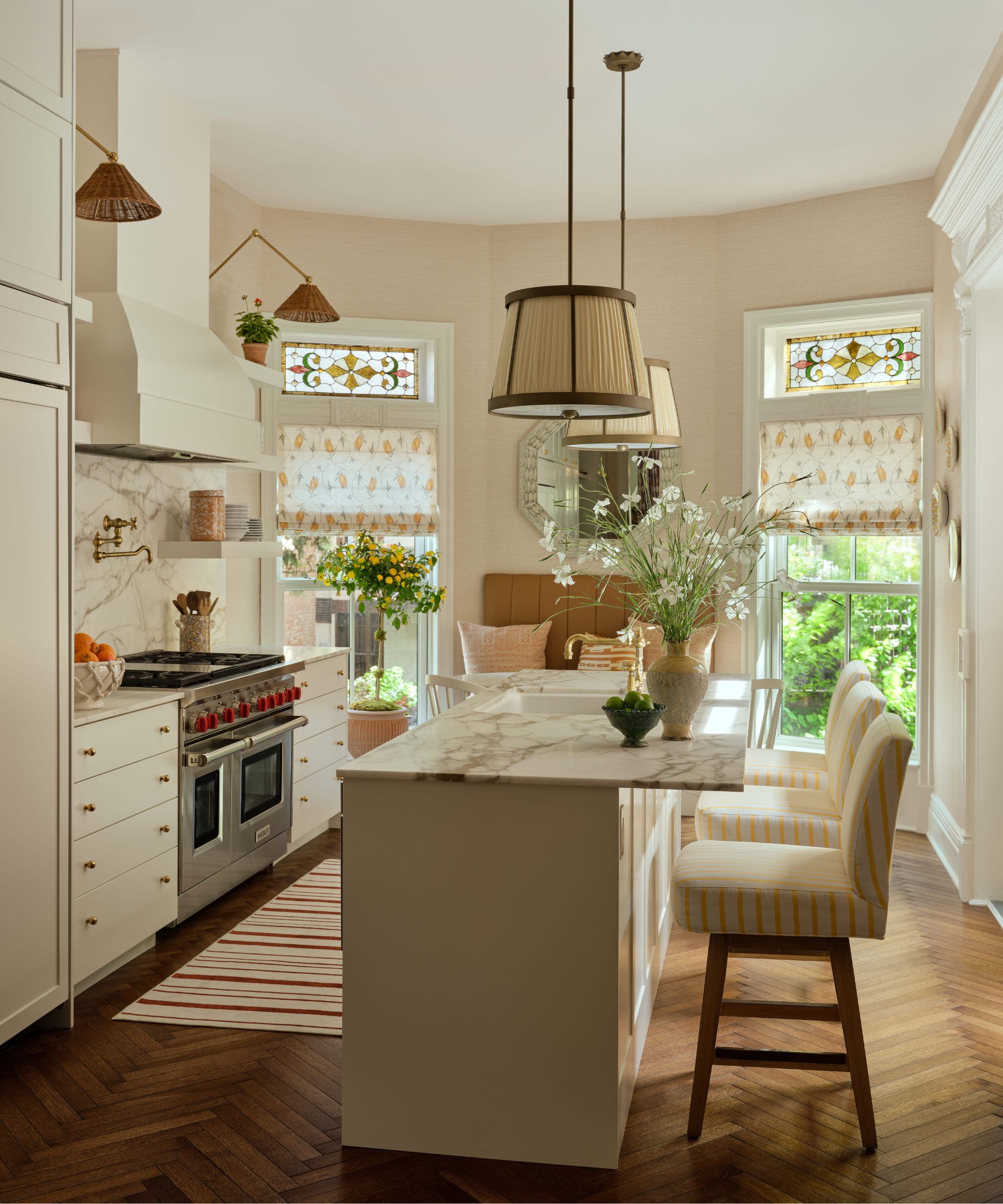 a small New York brownstone kitchen with blush pink walls, white cabinetry, a small island and a breakfast nook tucked by the windows