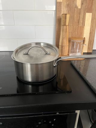 A stainless steel pan on a black glass stove top