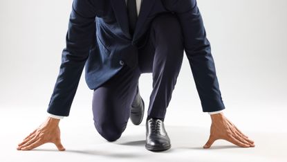 Businessman in starting position for run on white background, closeup