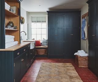 dark blue utility room with floor to ceiling cupboards, worktop and butler sink