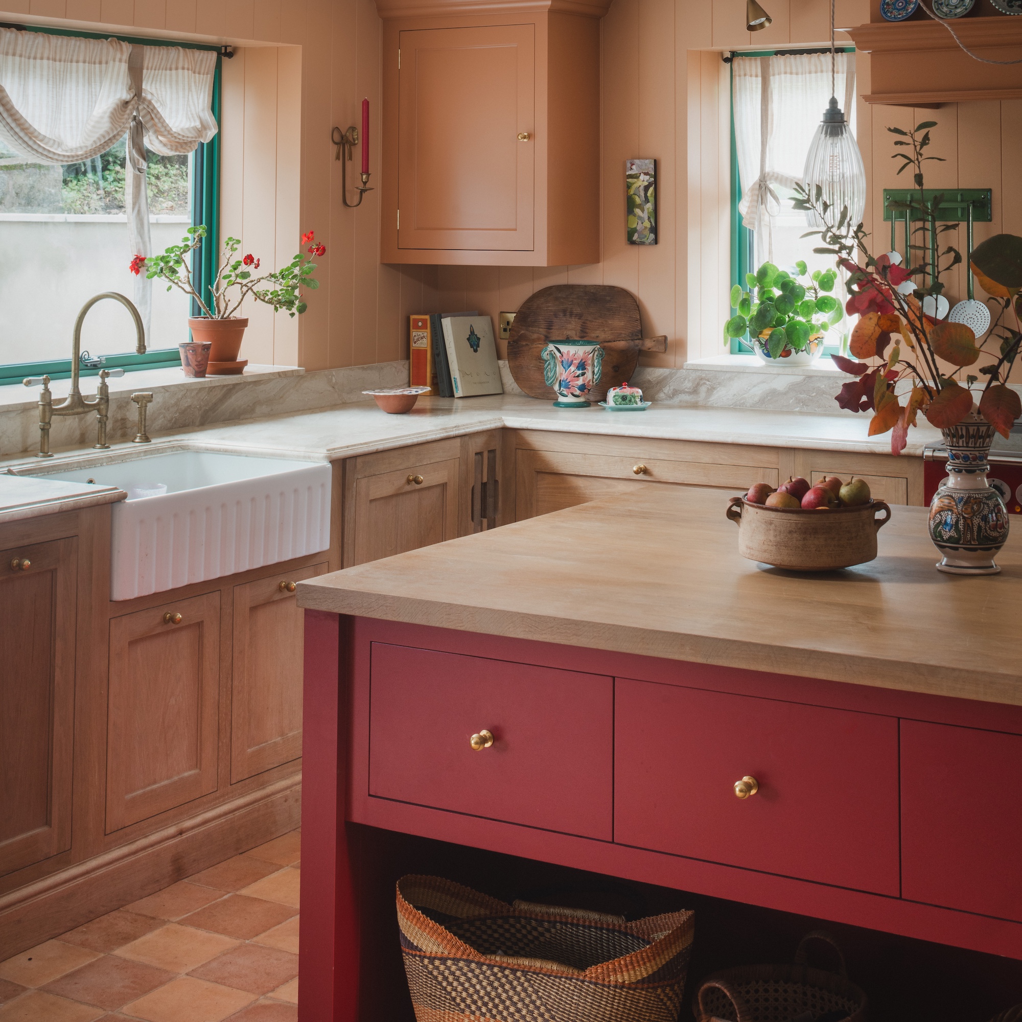 red painted island in wooden kitchen with white fluted butlers sink and swan neck tap