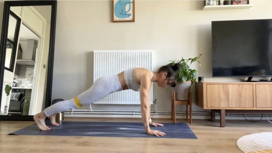 Writer Sam performing plank jacks banded at home on exercise mat