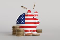 Piggy bank having the pattern of the national flag of the USA surrounded by stacks of gold coins in white background