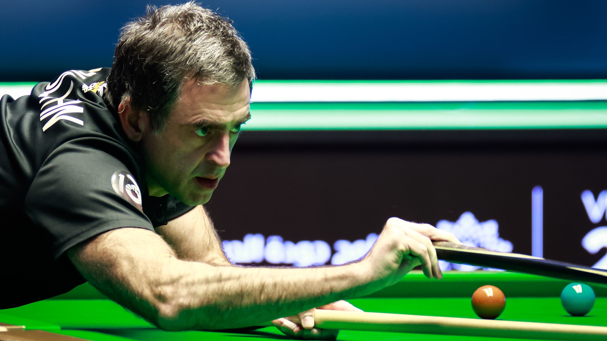 A professional snooker player focuses on a shot during a tournament match.